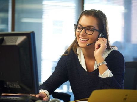 Female customer support representative wearing headset and smiling at desk