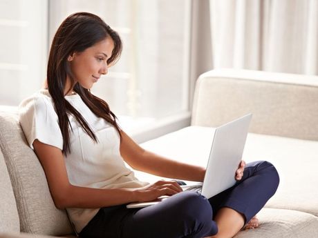 Woman sitting on a sofa using a laptop at home
