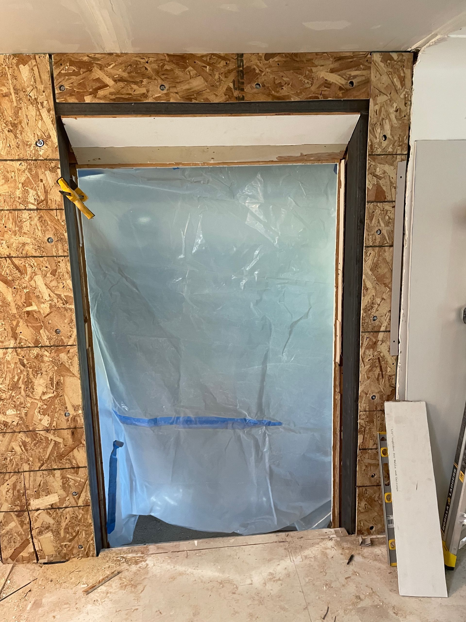 Doorway under construction, framed with OSB and plastic sheeting to contain dust.