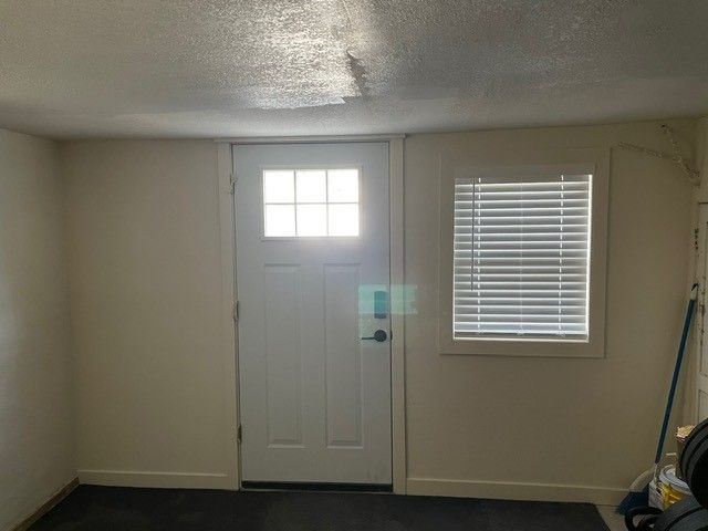 White interior room with a door and window, with sunlight shining through the door.
