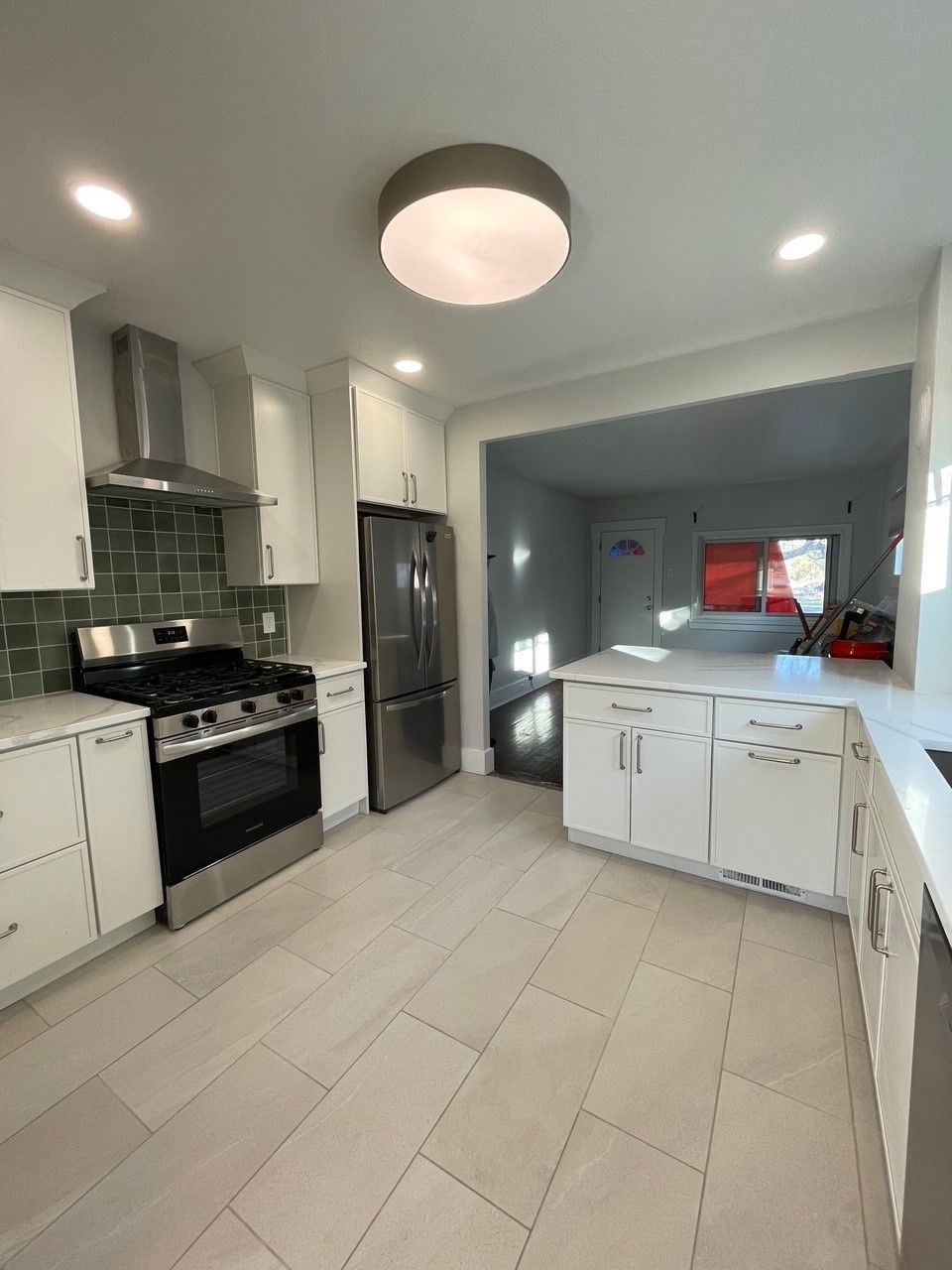 Modern kitchen with white cabinets, ss appliances, and light tile floors. Features a pass-through to another room.
