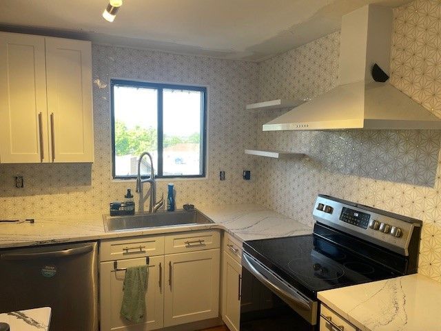 Modern kitchen with white cabinets, stainless steel appliances, and patterned backsplash.