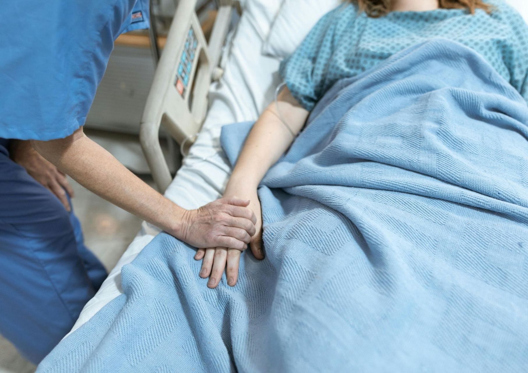 a nurse is holding the hand of a patient in a hospital bed