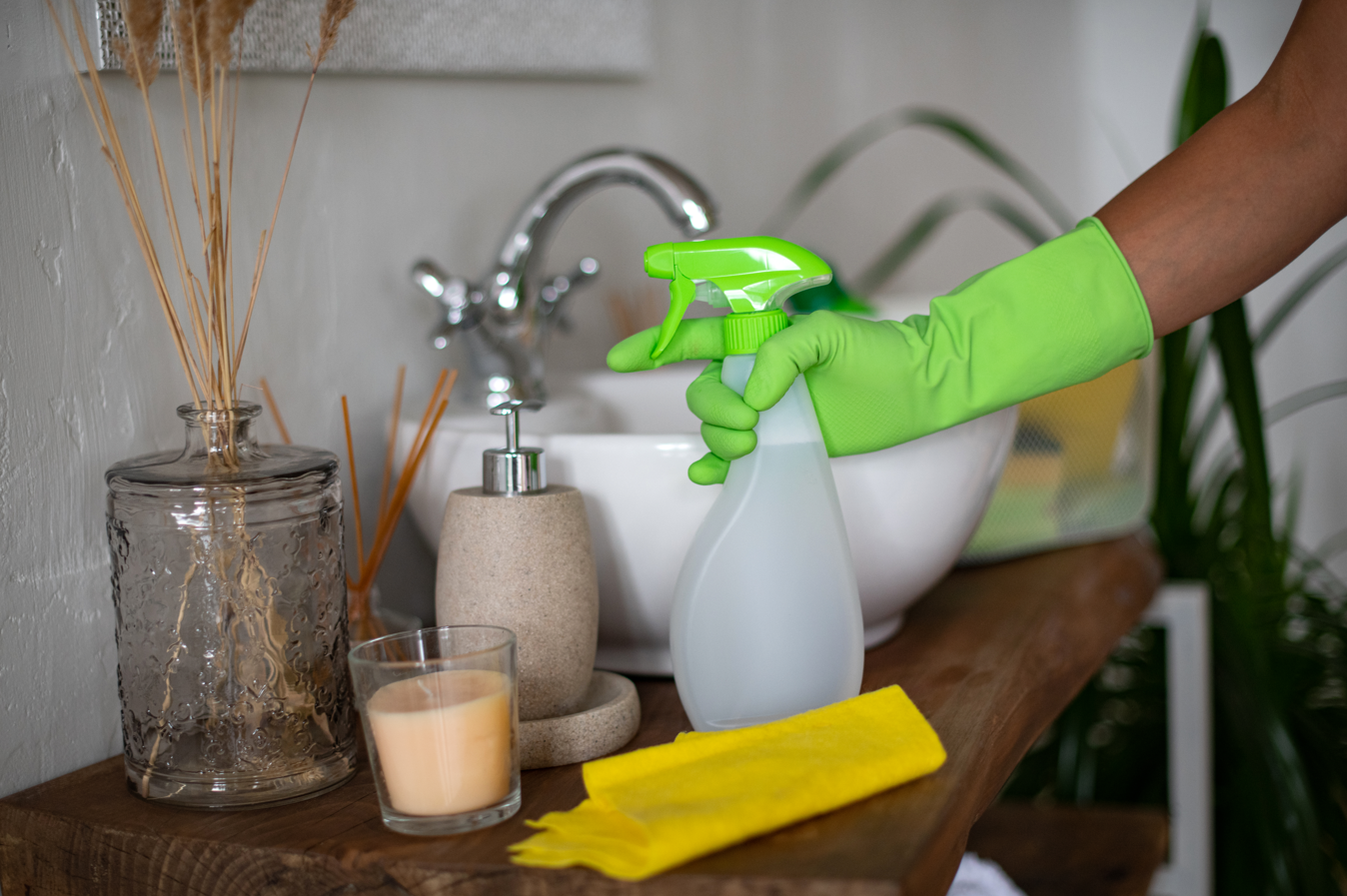 A person is cleaning a bathroom sink with a spray bottle.