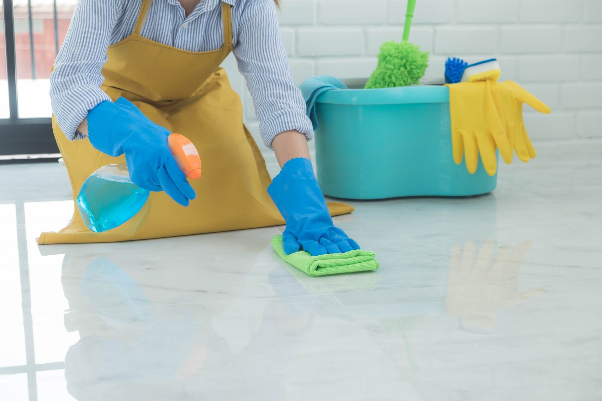 A woman is cleaning the floor with a mop and a spray bottle.