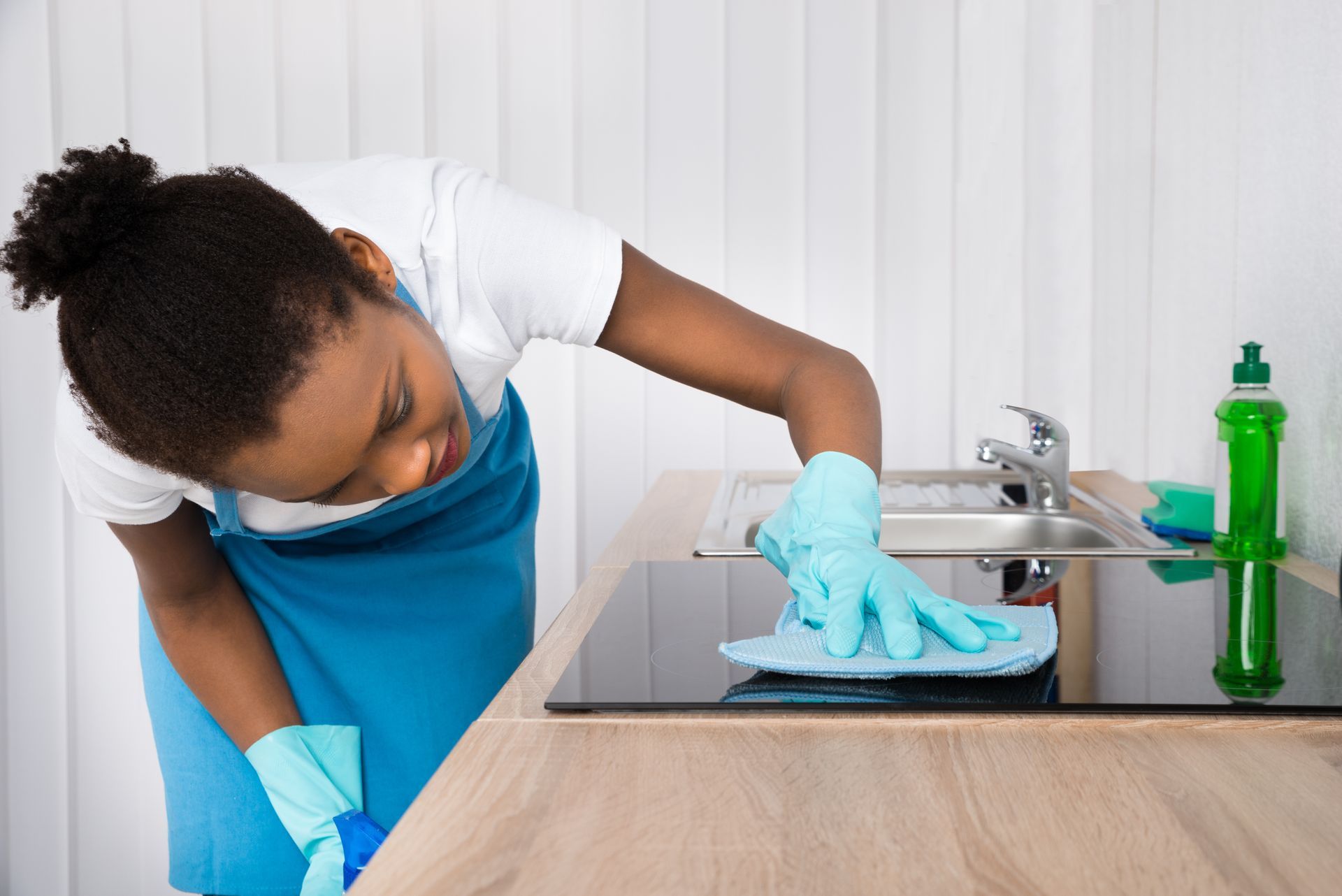 A woman is cleaning a kitchen counter with a cloth.