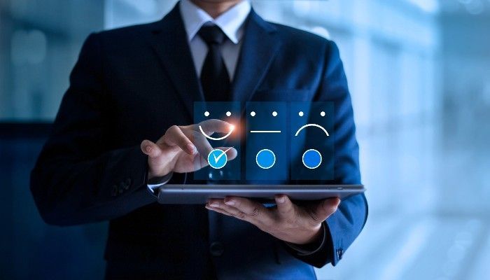 Man in a suit using a tablet, interacting with satisfaction icons.