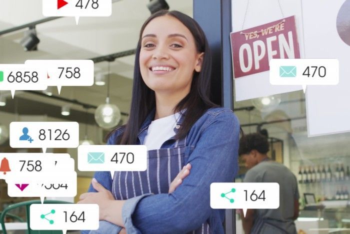 Woman in apron smiles by open shop door, surrounded by social media notification icons.