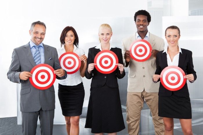 Business team holding targets, smiling in a modern office setting.