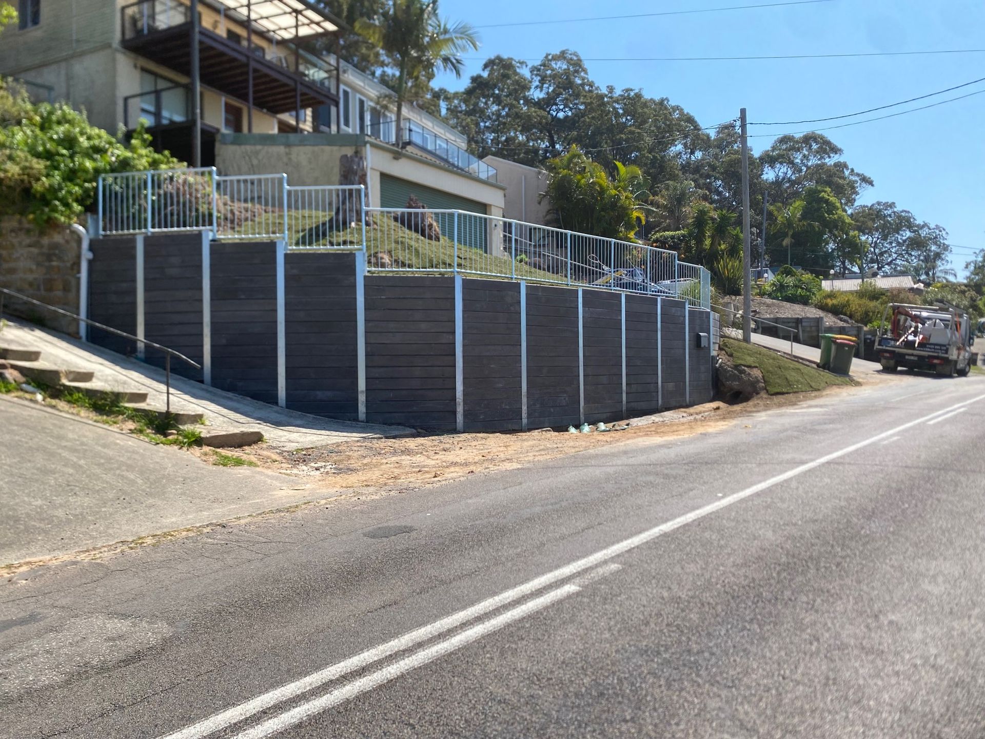 Hillside Home Behind a White Fence Along a Sloped Road — Lakecrest Projects in Belmont North, NSW