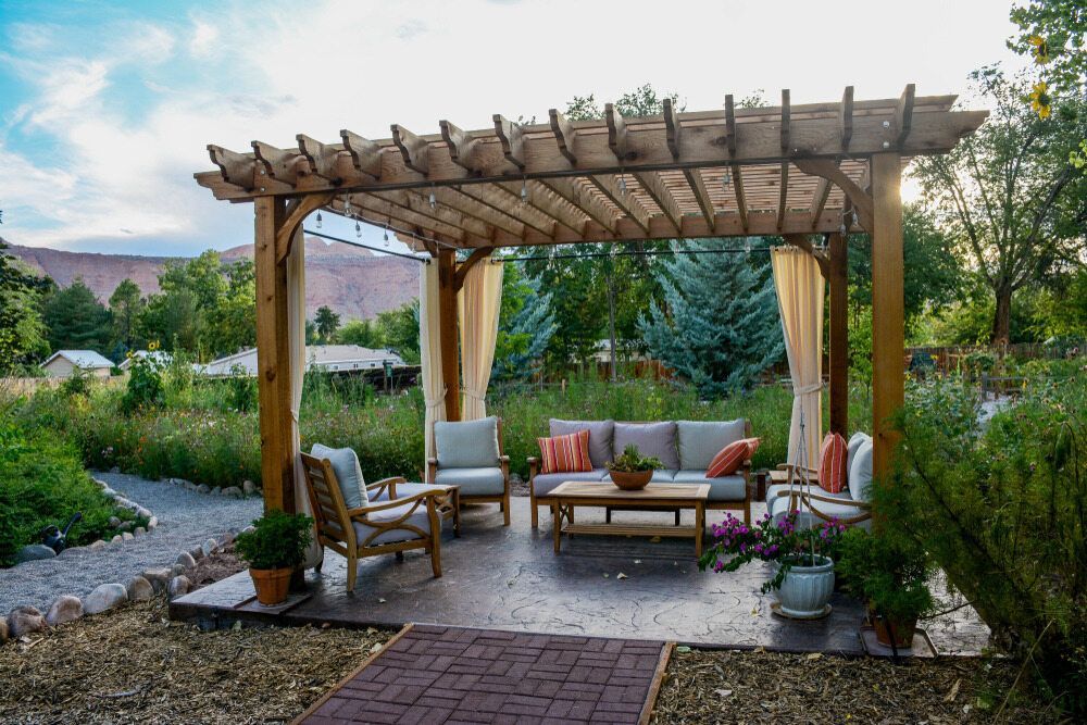 There is a Pergola With a Couch and Chairs Underneath It — Lakecrest Projects in Belmont North, NSW