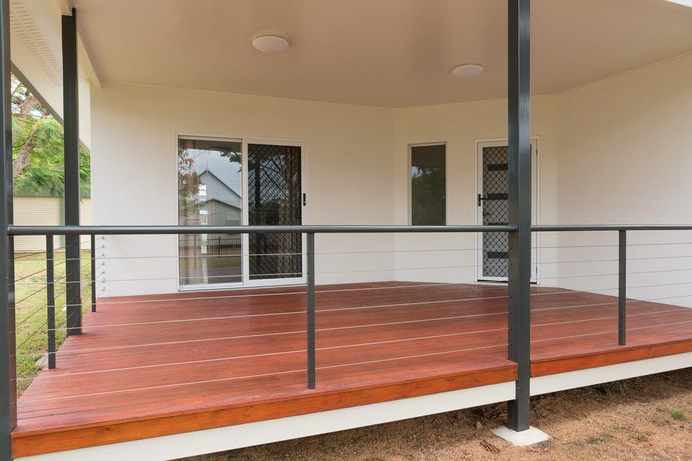 An Empty Porch With a Wooden Deck and a Black Railing — Lakecrest Projects in Lake Macquarie, NSW