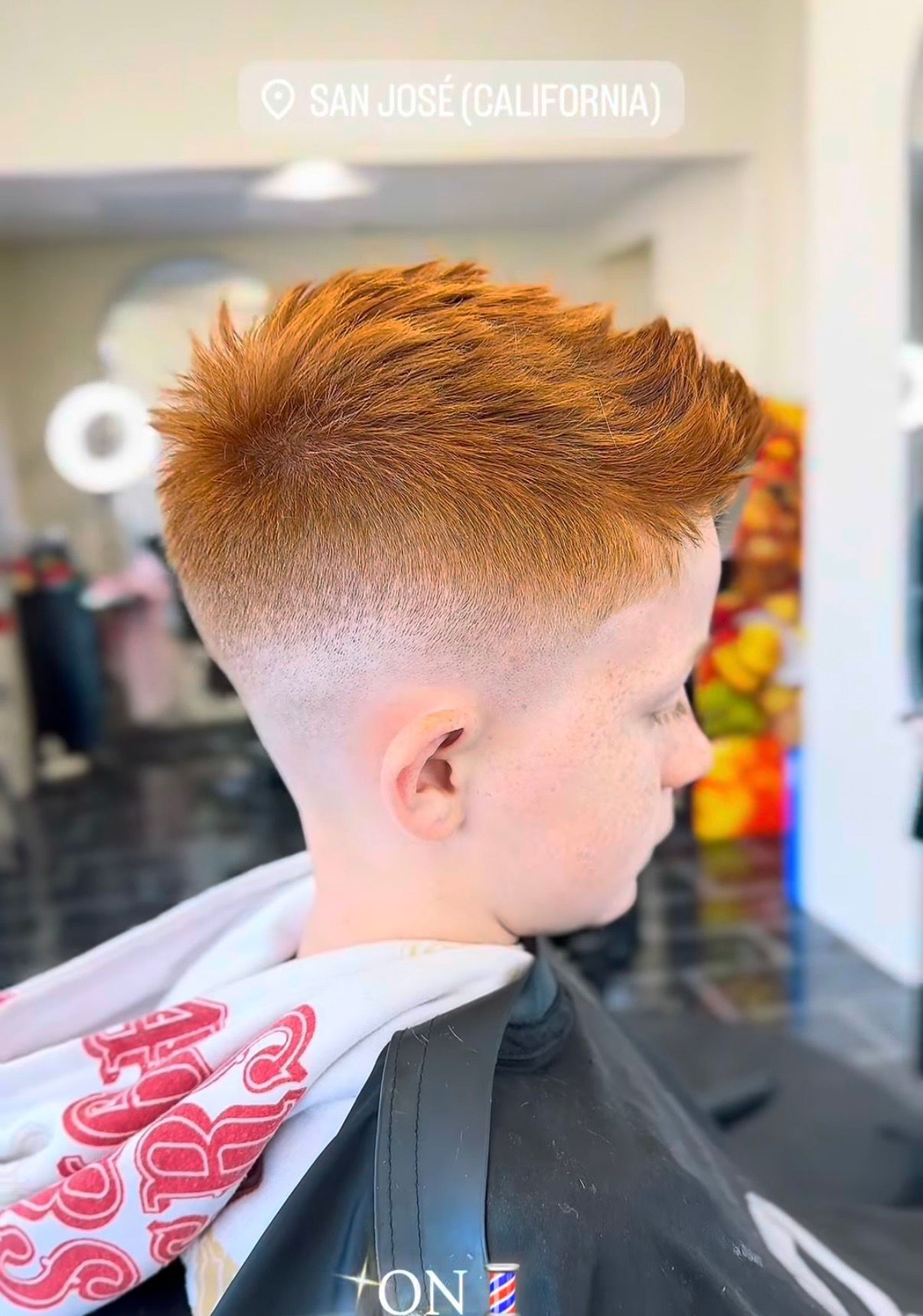 A side view of a person with a short, dark haircut featuring a precise, geometric star-shaped shave design on the side.