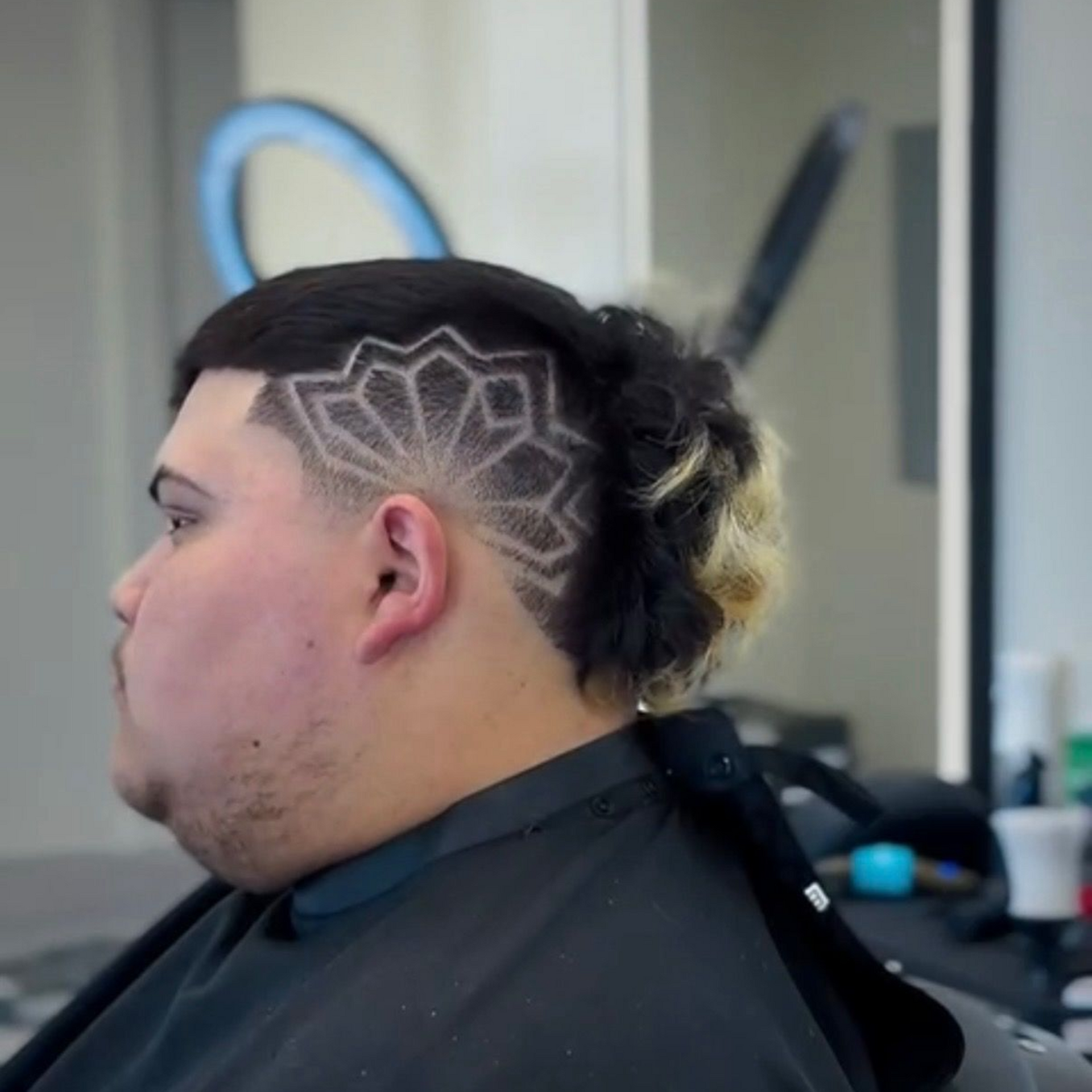 A close-up of a barber’s gloved hand styling a person's hair with a precision skin fade on the side.