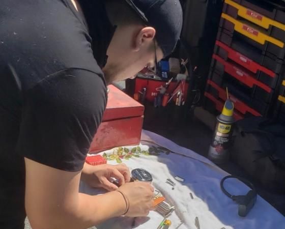 Person working on parts laid out on a white cloth, next to a toolbox.