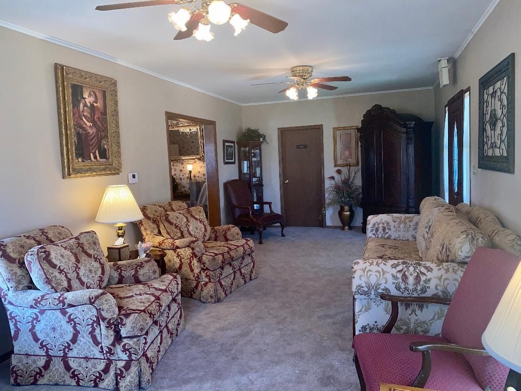 Living room with patterned furniture, artwork, and an antique cabinet.