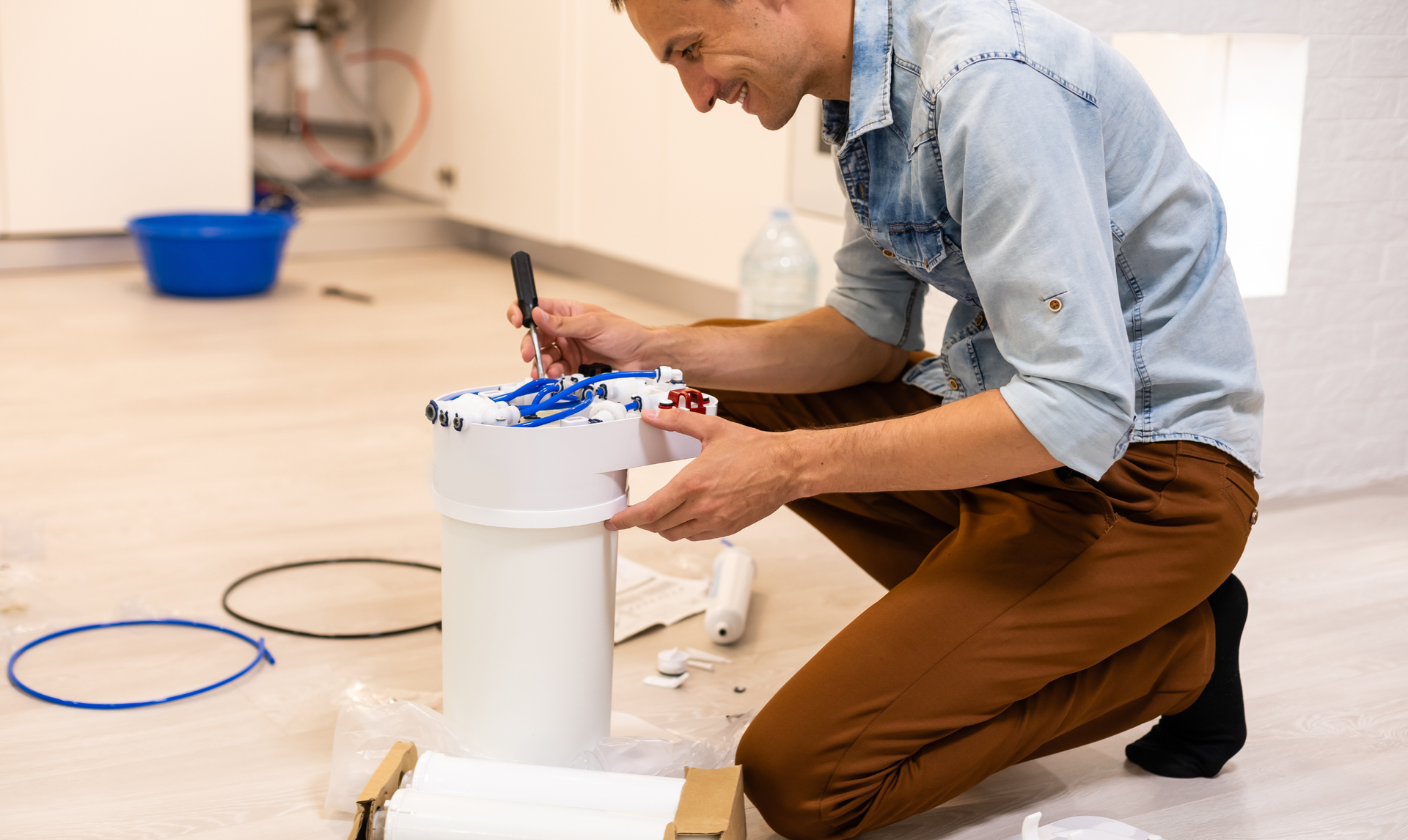 Person kneeling and checking a white cylindrical container on a wooden floor,.