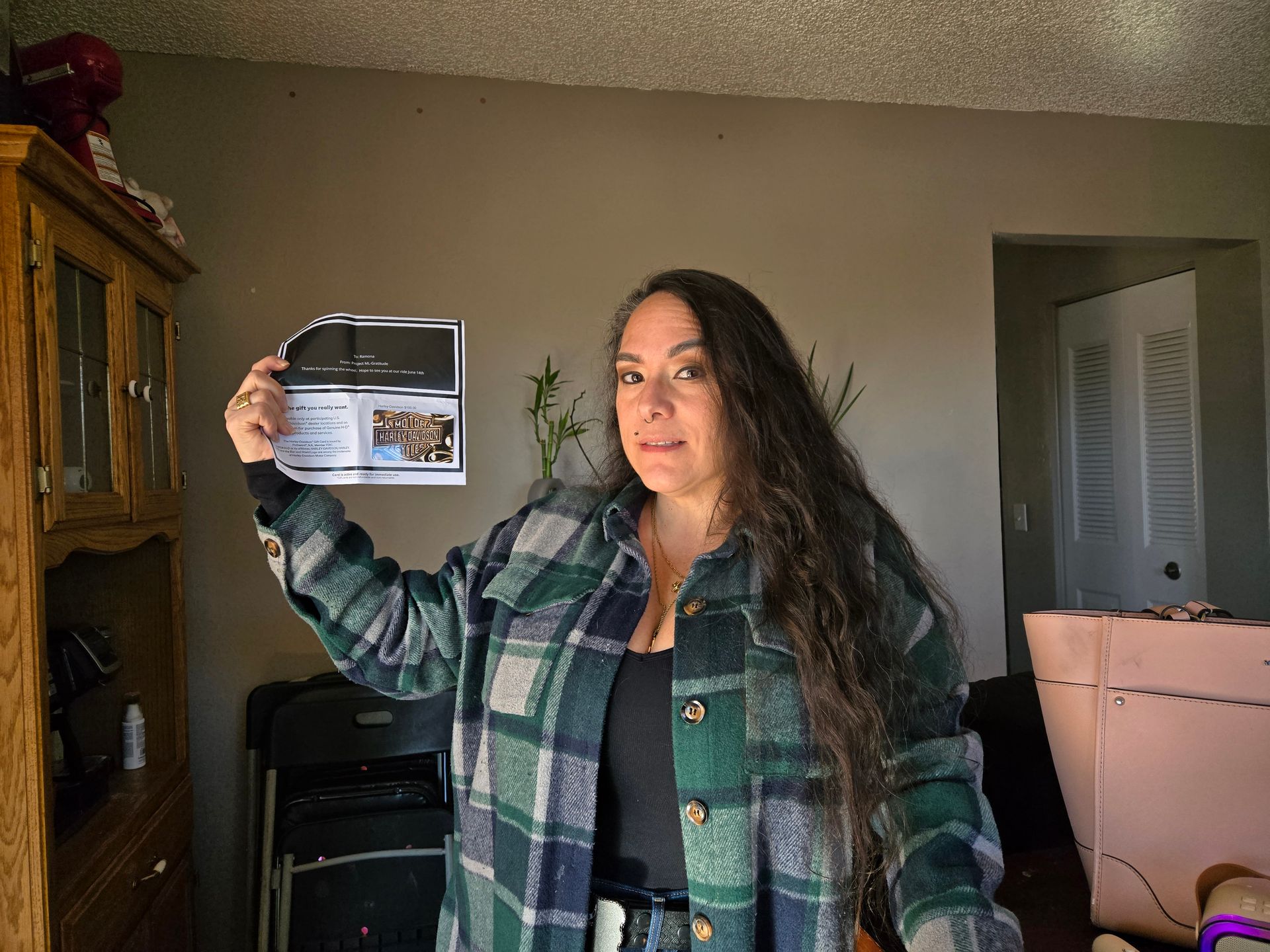 A woman in a plaid shirt is holding a piece of paper in a living room.