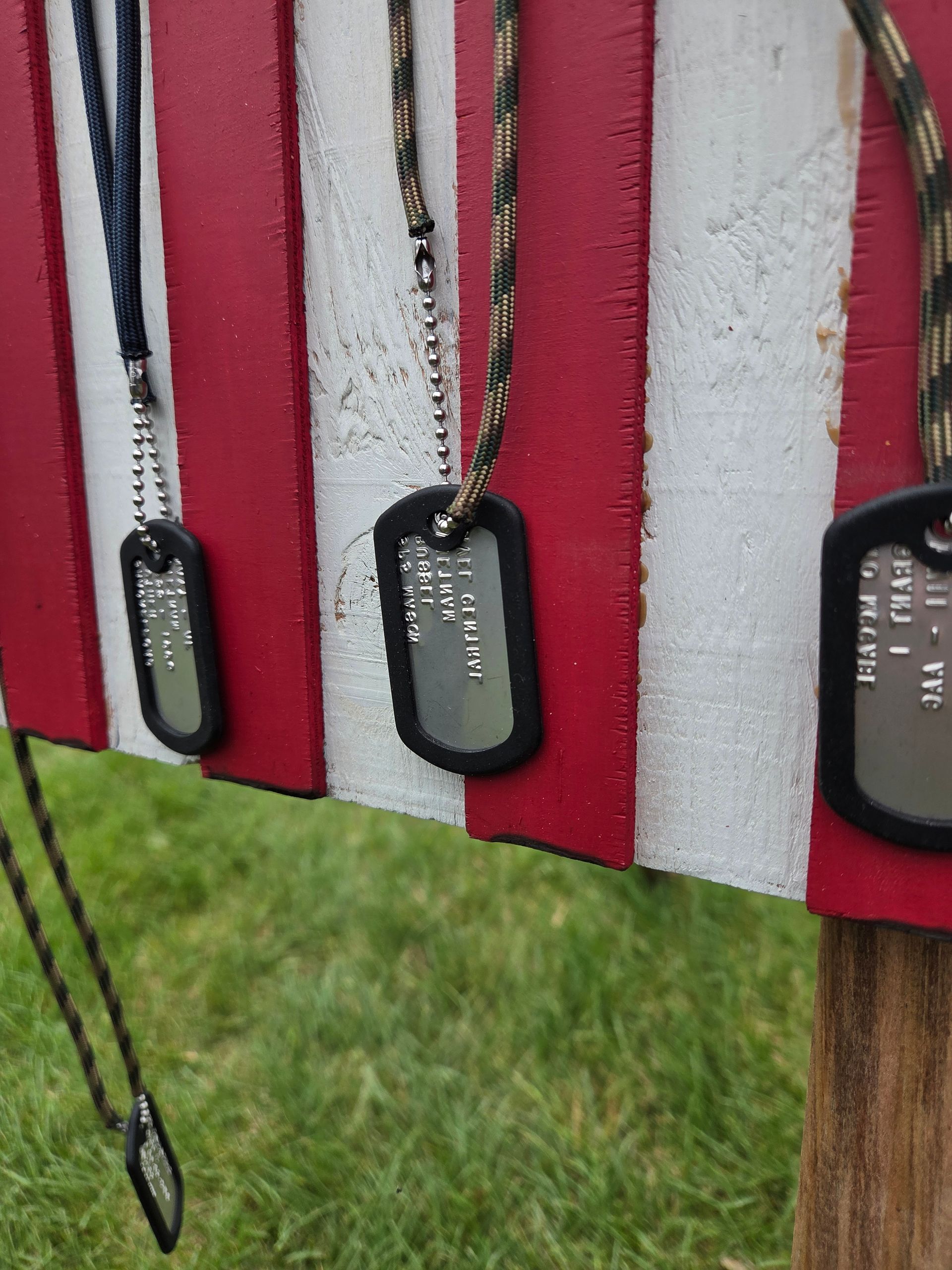 A bunch of dog tags are hanging on a red and white striped board