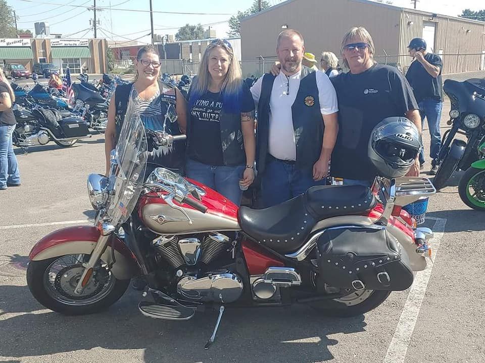 A group of people standing next to a motorcycle in a parking lot.
