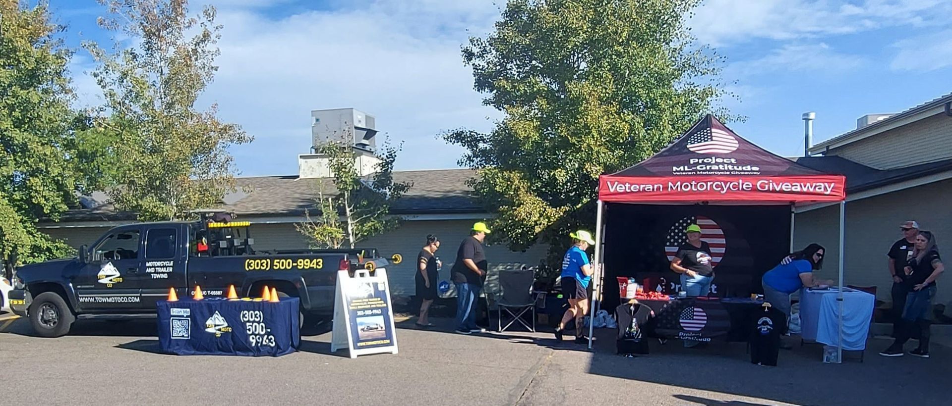 A group of people are standing around a tent in a parking lot.