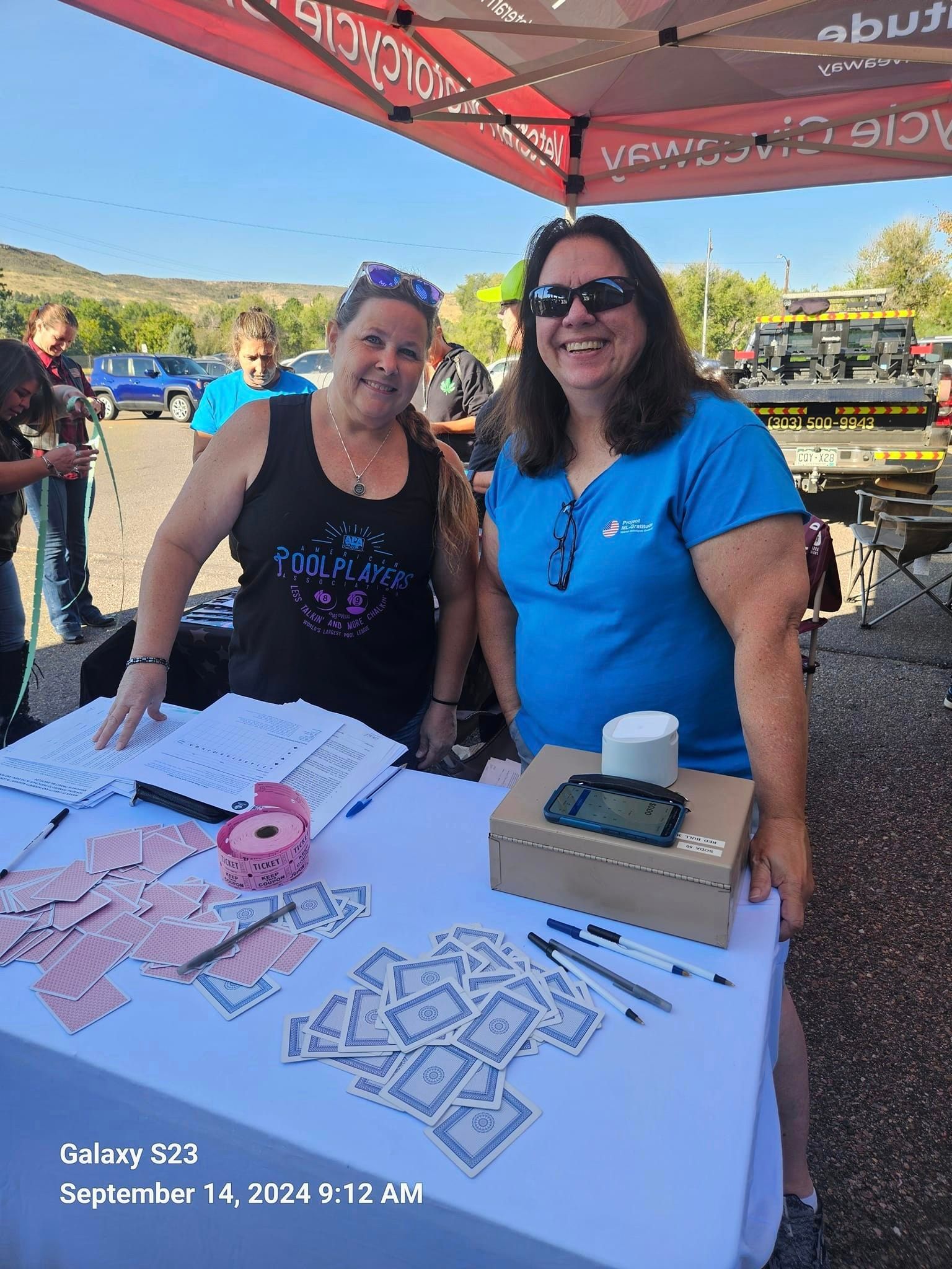 Two women are standing next to each other at a table.