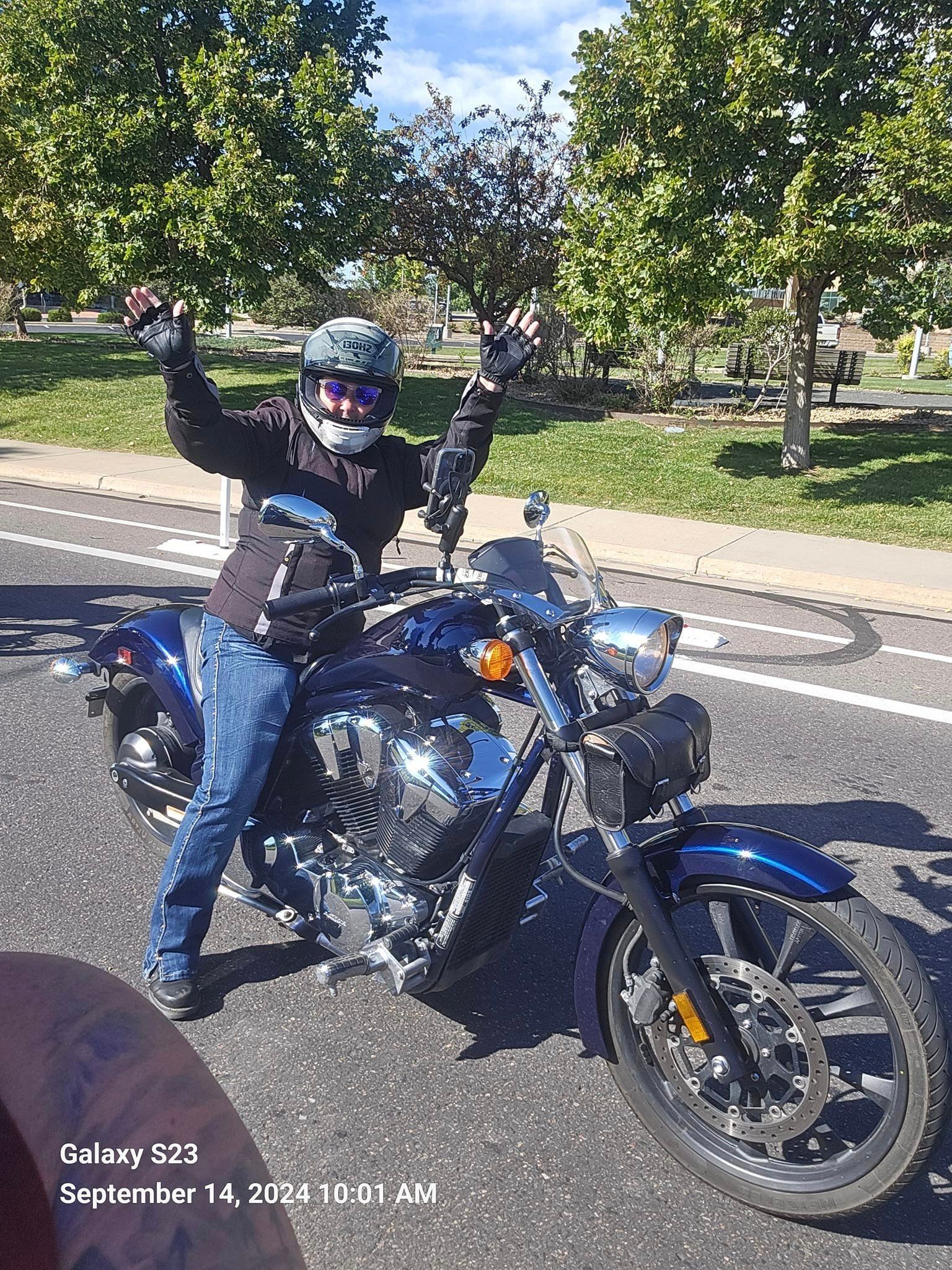 A man is standing next to a motorcycle on the side of the road.