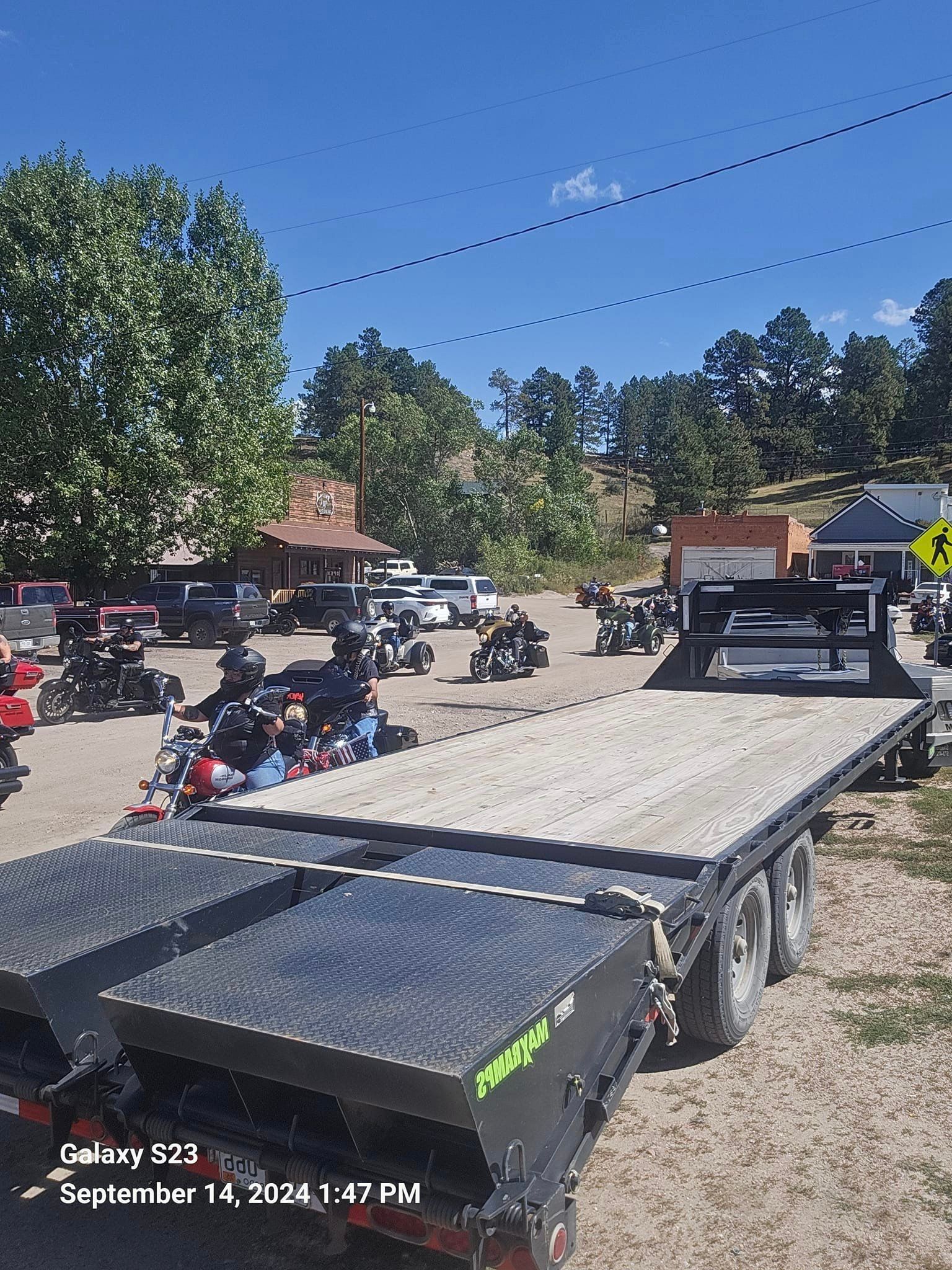 A group of people are riding motorcycles on a trailer in a parking lot.