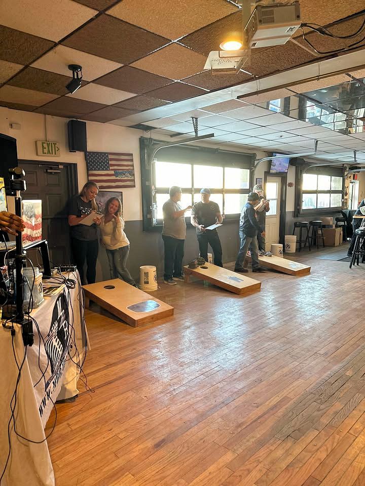 A group of people are playing cornhole in a large room.