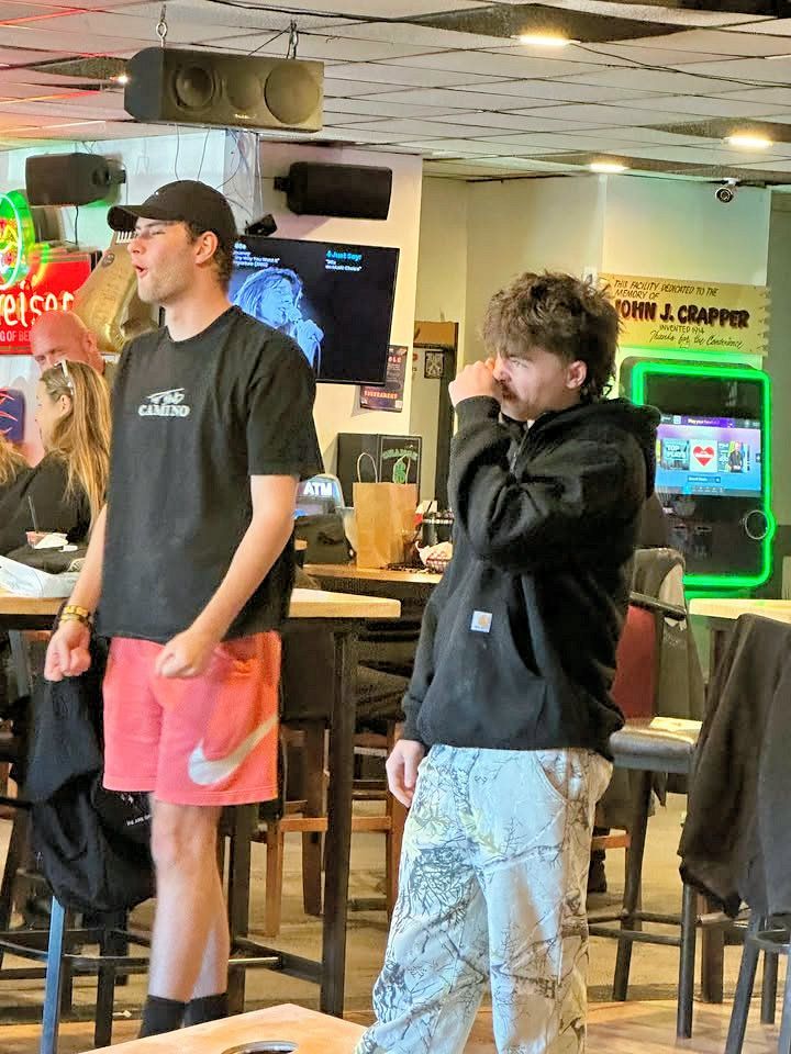 Two men are standing in a restaurant talking to each other.