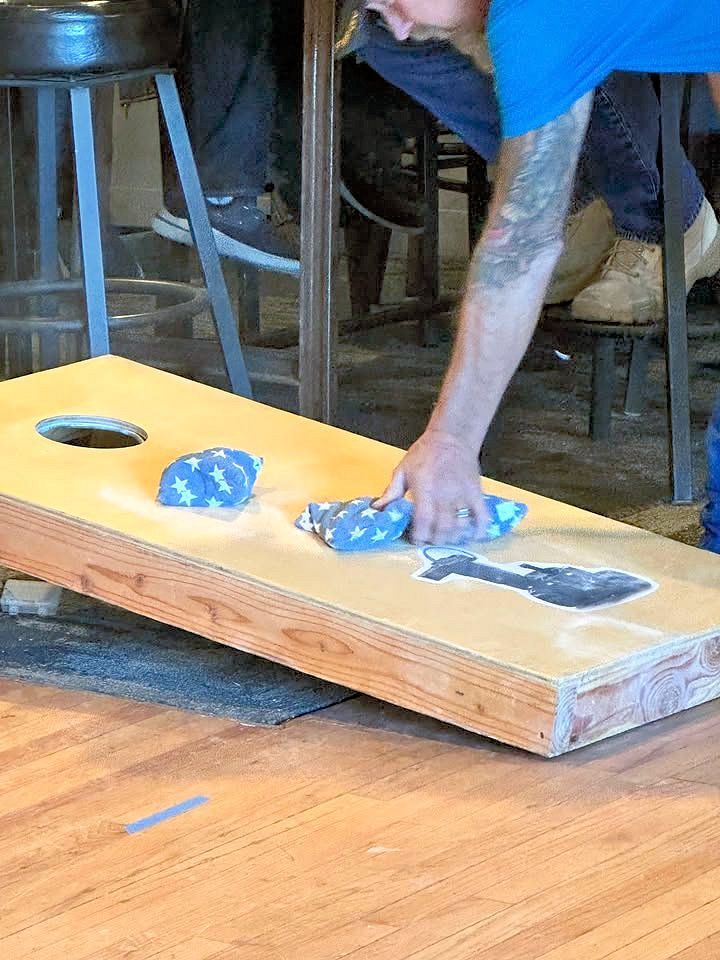 A man is playing a game of cornhole on a wooden table.