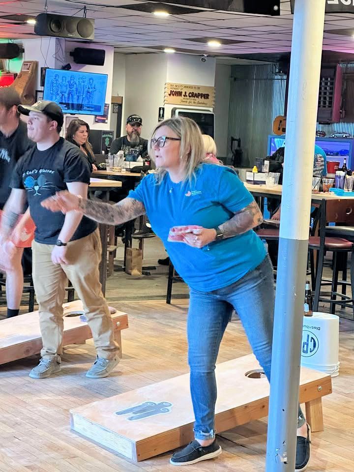 A group of people are playing a game of cornhole in a restaurant.