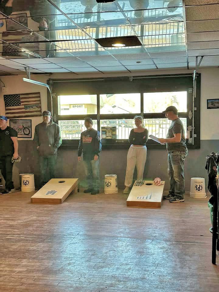 A group of people are playing cornhole in a room.