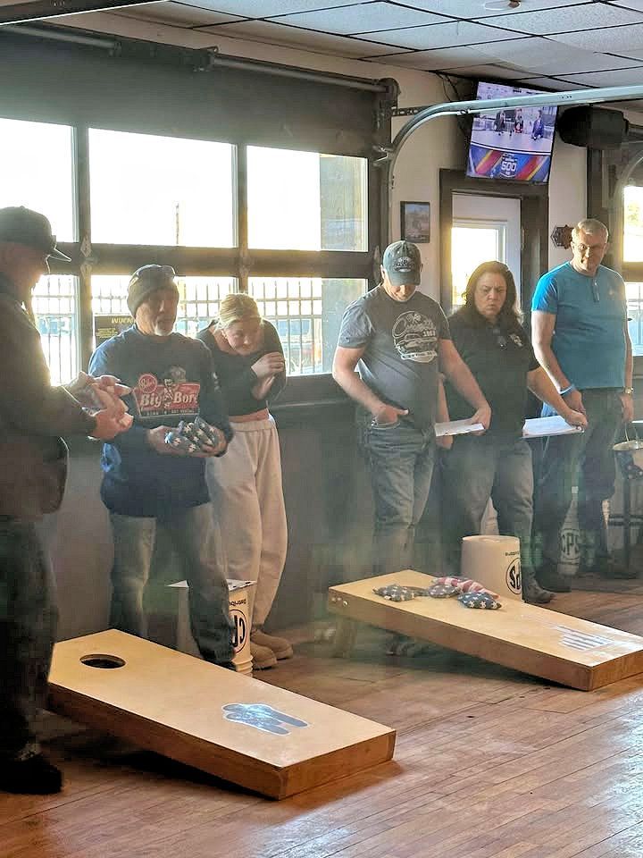 A group of people are playing cornhole in a room.