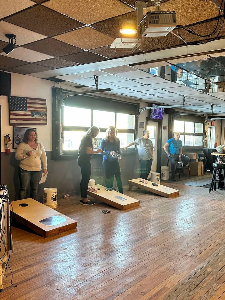 A group of people are playing cornhole in a large room.