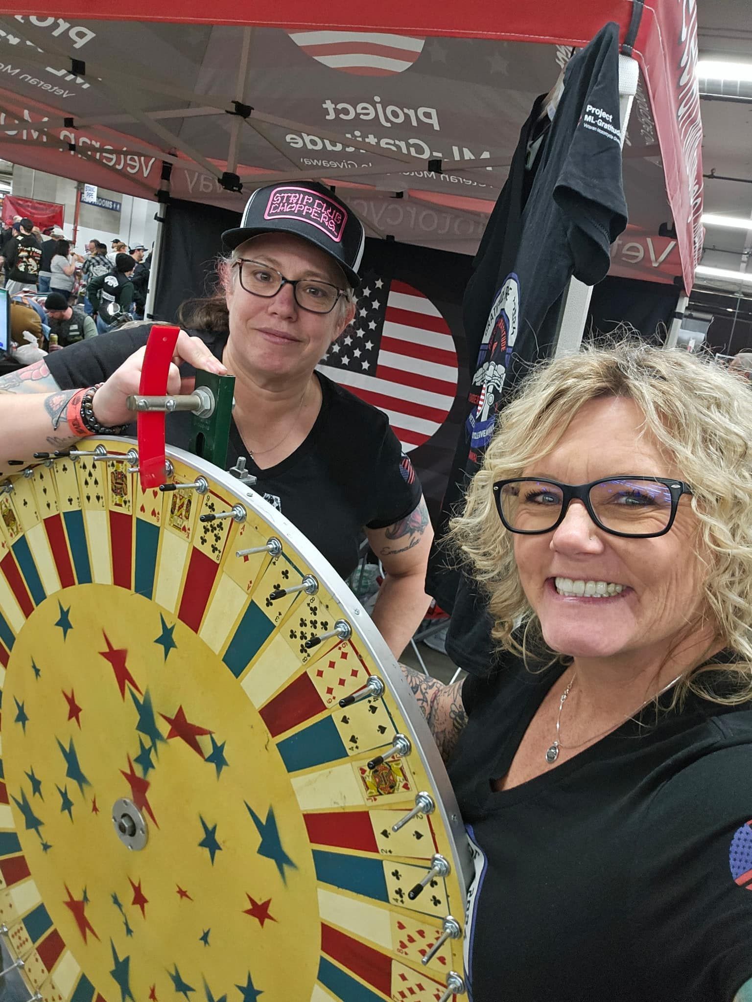 Two women are standing next to each other holding a spinning wheel.