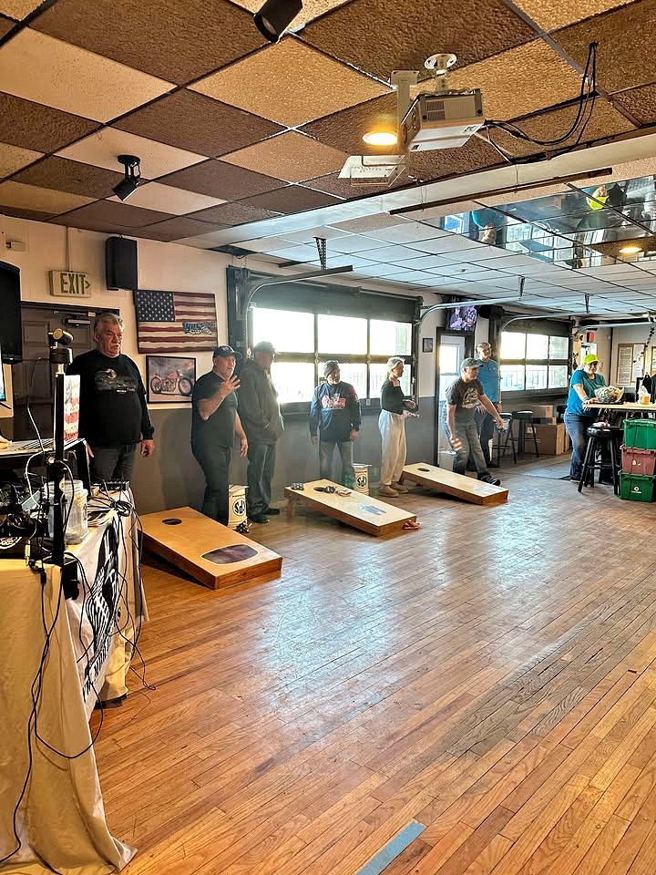 A group of people are playing cornhole in a large room.
