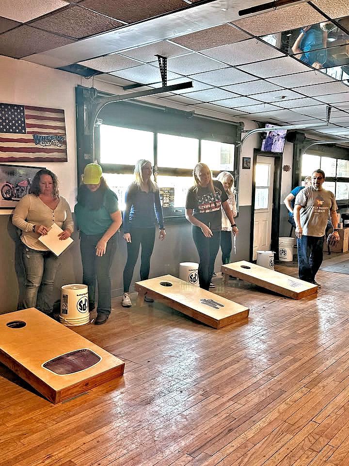 A group of people are playing cornhole in a room.