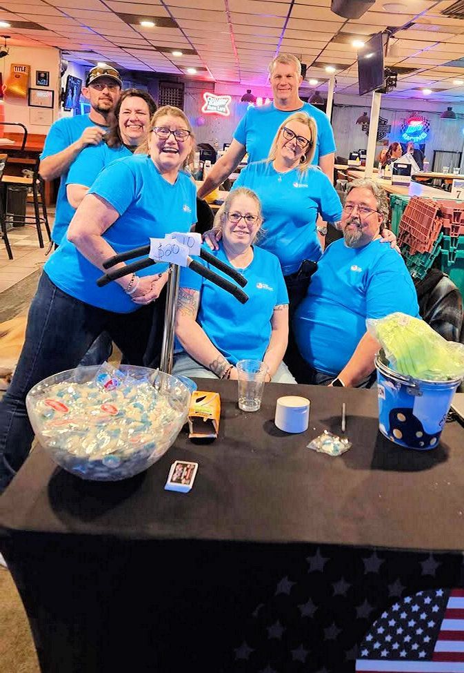A group of people are posing for a picture in a bowling alley.