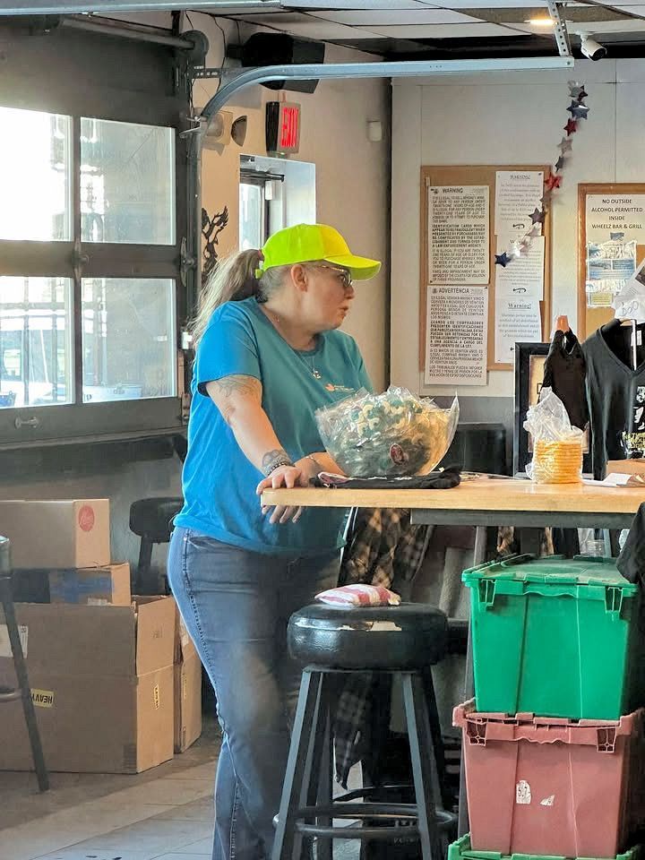 A woman in a yellow hat is standing at a table with a bag of chips on it.