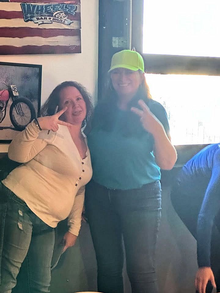 Two women are posing for a picture in a restaurant.