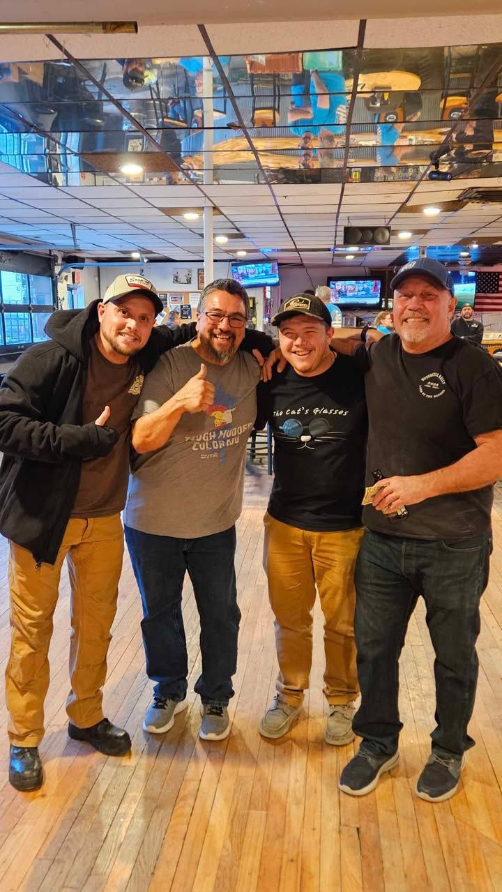 A group of men are posing for a picture in a bowling alley.