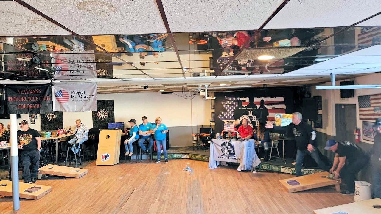 A group of people are playing cornhole in a room.