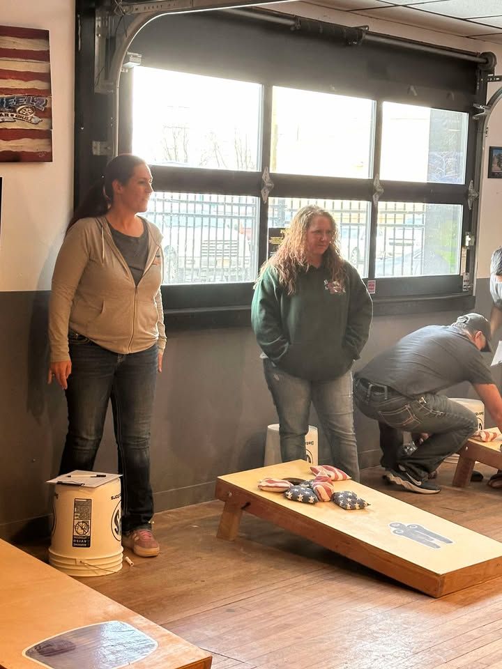 A group of people are playing a game of cornhole in a room.