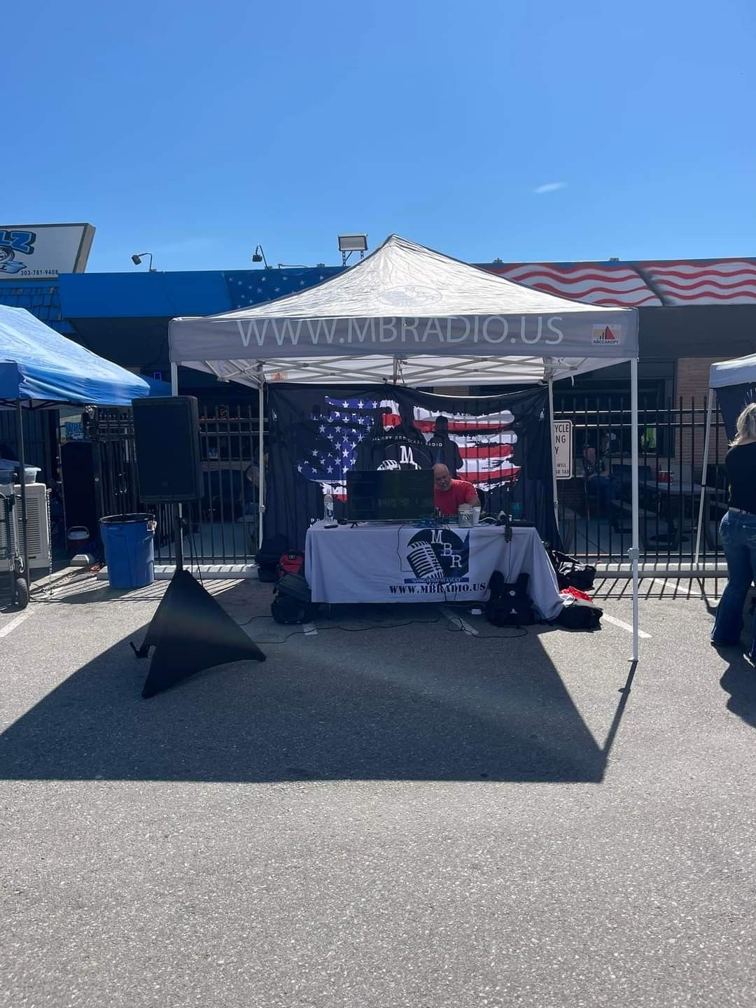 A tent with an american flag on it is in a parking lot.