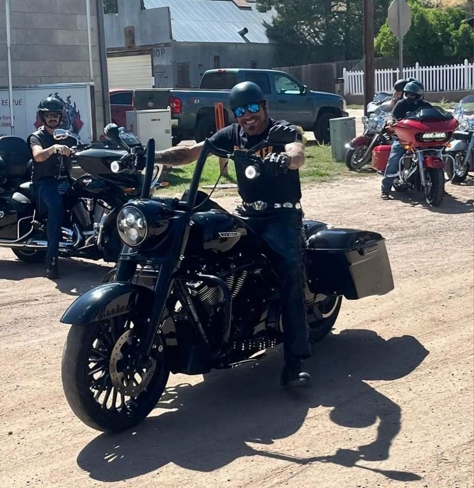 A man wearing sunglasses is riding a motorcycle on a dirt road