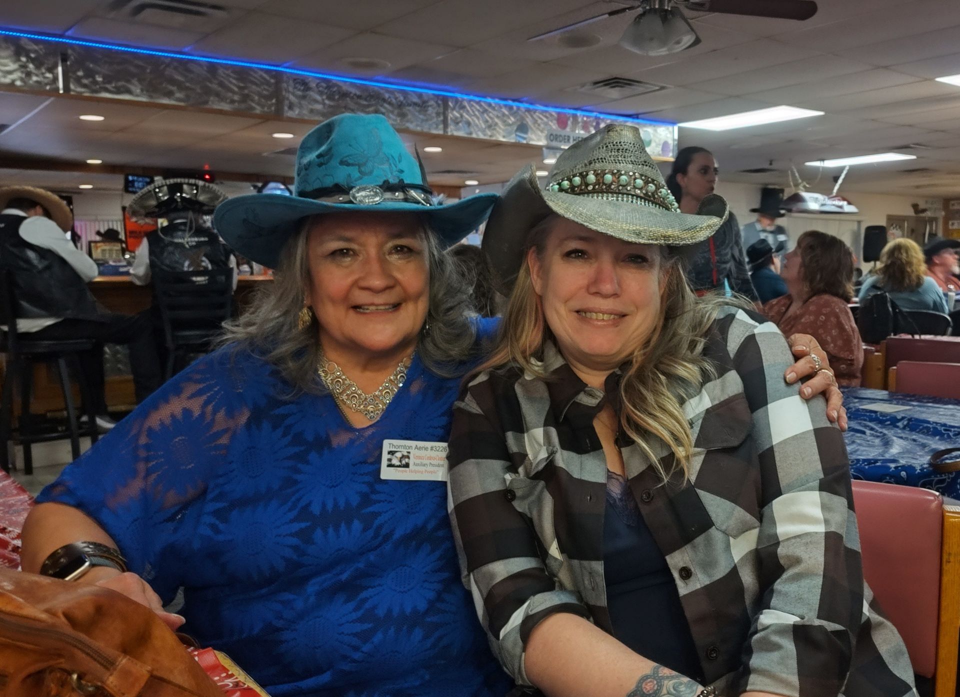 Two women wearing cowboy hats are posing for a picture in a restaurant.