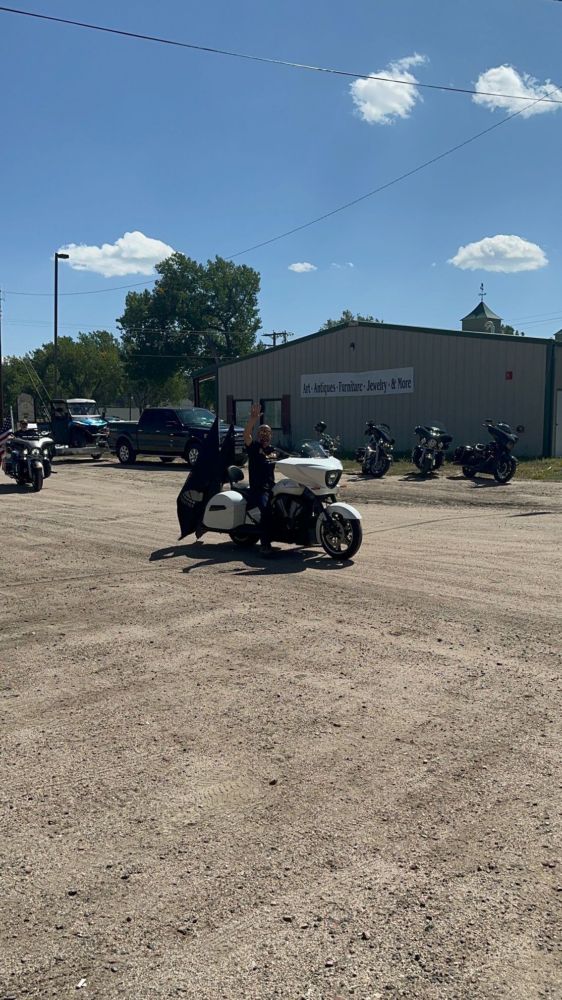 A group of motorcycles are parked in a gravel lot in front of a building.