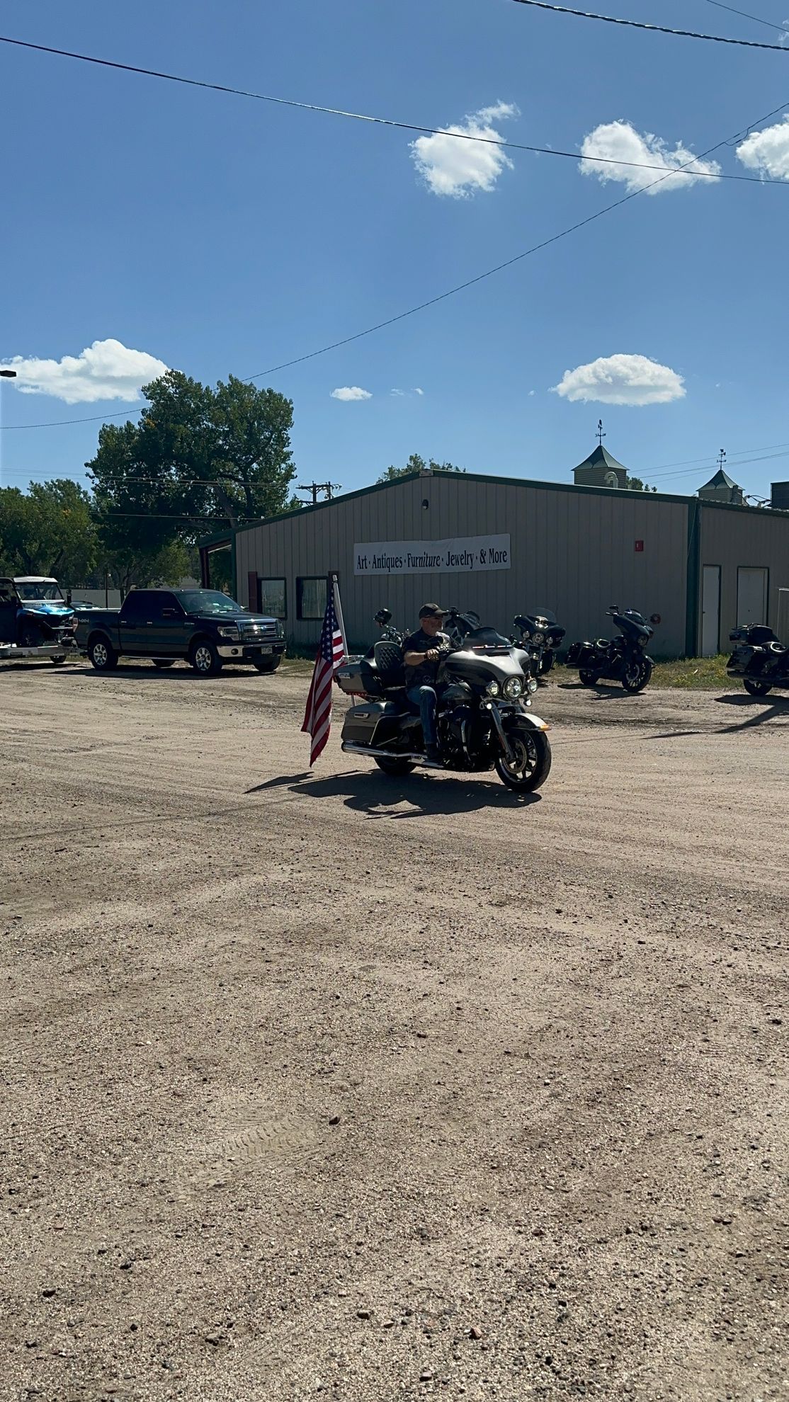 A man is riding a motorcycle in a dirt parking lot.