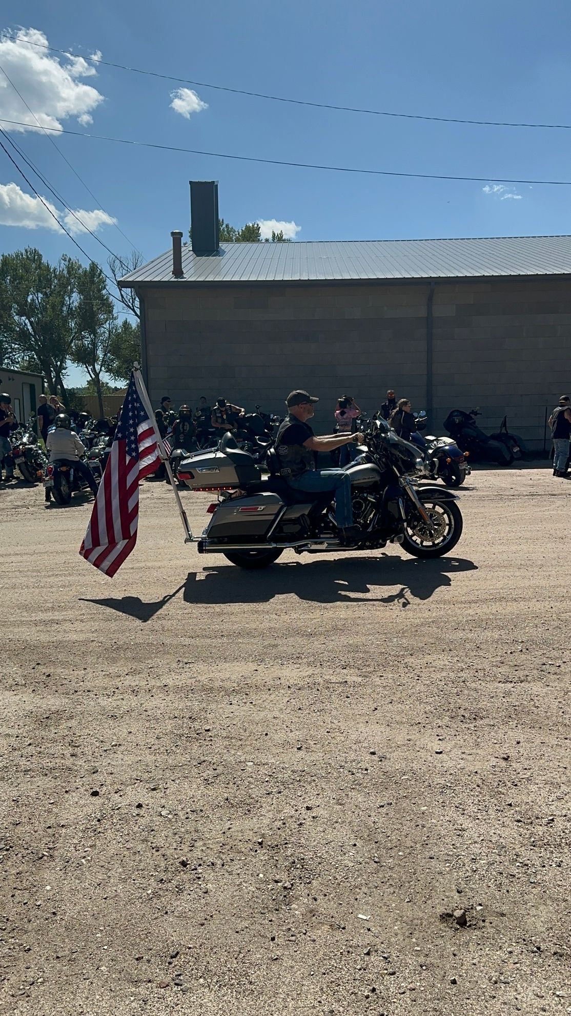 A man is riding a motorcycle with an american flag attached to it.